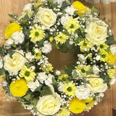 Elegant Yellow & White Wreath - This elegant wreath is a heartfelt tribute, symbolizing peace, remembrance, and love. Featuring ivory roses, yellow chrysanthemums, white carnations, and delicate sprays of baby’s breath, it is thoughtfully arranged with soft greenery for a timeless finish. The gentle combination of yellow and white blooms conveys both warmth and serenity, offering comfort and compassion in times of loss.