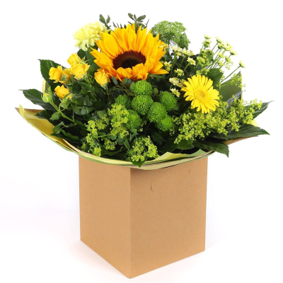Golden Glow - Brighten someone's day with the `Golden Glow` arrangement, featuring a stunning sunflower mix with seasonal blooms. Complemented by lush green foliage, this arrangement brings a touch of nature's radiant beauty into any space.